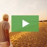 clickable video thumbnail showing a retired couple walking along the beach at sunset