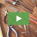 clickable video thumbnail depicting a variety of tools scattered on a wooden table