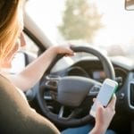 a young woman is distracted by her phone while driving