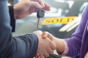 Used car seller hands the keys to a buyer while shaking hands